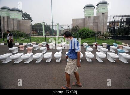 Jakarta. 3rd Dec, 2015. People pass by water closets displayed during a protest in front of the House of Representative building in Jakarta, Indonesia. Dec. 3, 2015. An Indonesian minister testified against the House of Representative's speaker Wednesday, accusing him of trying to convince the regional director of a mining giant that its license could be extended in exchange for shares. © Agung Kuncahya B./Xinhua/Alamy Live News Stock Photo