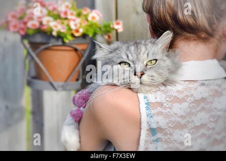 Rear view of a girl holding a cat over her shoulder Stock Photo