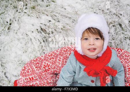 Girl sitting on a blanket in the snow Stock Photo
