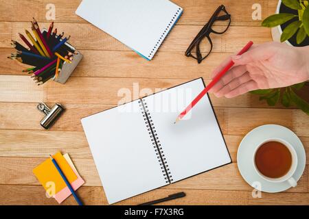 Composite image of hand holding red pencil Stock Photo