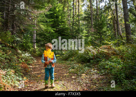 Boy standing in the forest holding a leaf