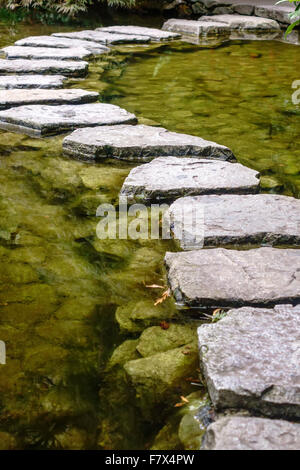 Stepping stones across a pond in Japanese garden Stock Photo