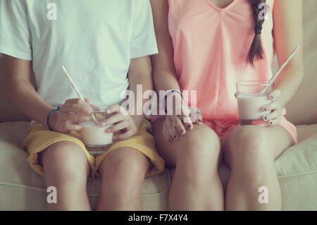 Boy and girl sitting on sofa with glass of milk Stock Photo