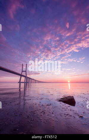 Vasco da Gama Bridge across River Tagus silhouetted against pink morning sky, Lisbon, Portugal Stock Photo
