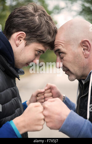 Man and teenage boy standing head to head Stock Photo