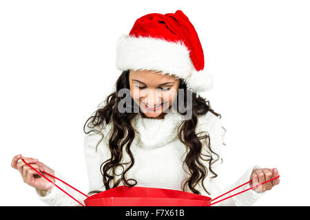 Happy woman with christmas hat looking in red shopping bag Stock Photo