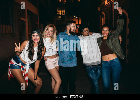 Group of young people celebrating outdoors posing for camera. Multi ethnic group of young friends enjoying in outdoor party. Stock Photo