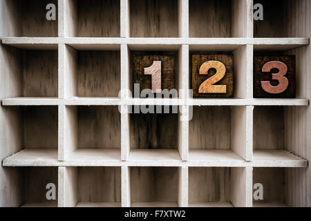 The numbers '123' written in vintage ink stained wooden letterpress type in a partitioned printer's drawer. Stock Photo