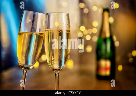 Image of two champagne glasses with bottle and blur lights in background Stock Photo