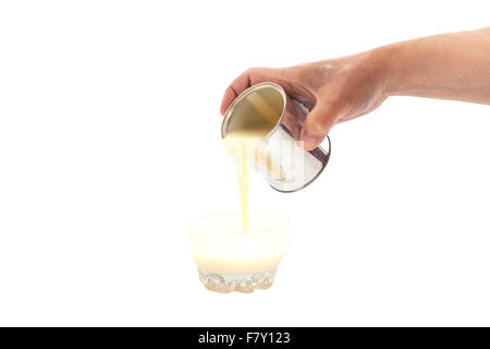 Man hand pouring condensed milk into a bowl isolated Stock Photo