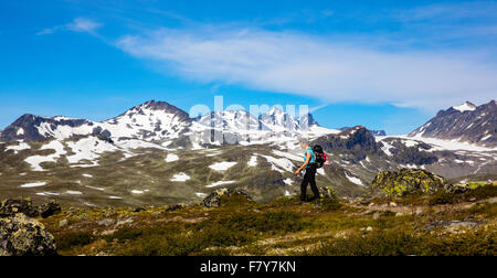 A female walking along the Memurubu to Gjendebu trail above Lake Gjende in the Jotunheimen National Park Norway Stock Photo