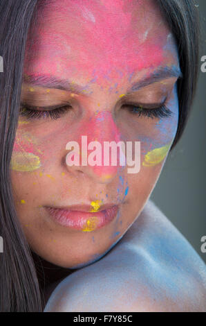 Closeup portrait of beautiful hispanic girl closing her eyes with painted face over gray background Stock Photo