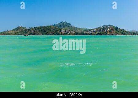 a tropical thai island with blue sky and vivid green waters Stock Photo