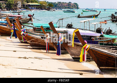 The bow of a traditional thai long tail boat decorated with ribbons and yellow flowers as a luck charm Stock Photo