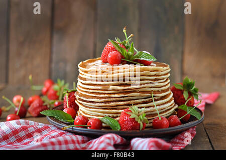 Pancakes with berries and syrup in a rustic style. Stock Photo