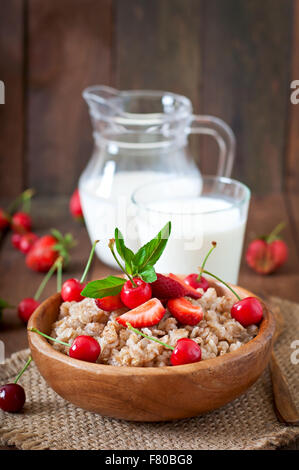Oatmeal porridge with berries in a wooden bowl Stock Photo