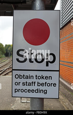 A large warning sign in white with black lettering and a large red disc on the top half, a warning to train Drivers and Guards to ensure token taken. Stock Photo