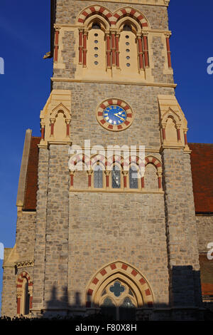 A view showing the lower stained glass windows with ornate stonework all cleaned with a blue faced clock below the bell area. Stock Photo