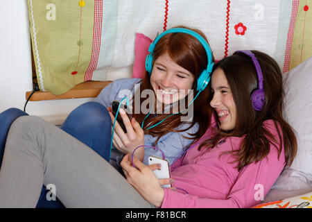 Girls, friends listening to music together with headphones, Upper Bavaria, Germany Stock Photo