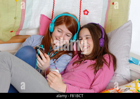 Girls, friends listening to music together with headphones, Upper Bavaria, Germany Stock Photo