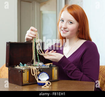 teenager girl looks jewelry in treasure chest at home Stock Photo