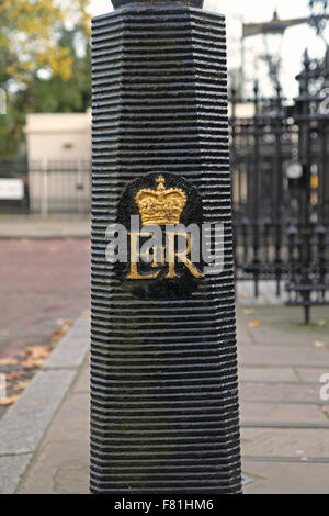 A Black painted ribbed Cast Iron bollard in Regents Park bearing a royal crown painted in gold. Stock Photo