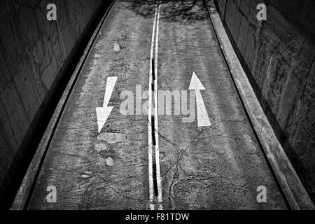 white arrows painted on a road in either direction viewed from above Stock Photo