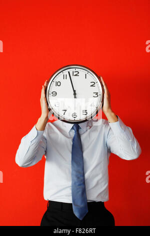Man with wall clock on red background, deadline concept Stock Photo