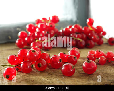 bunch of fresh redcurrants on a wooden table in a kitchen setting Stock Photo