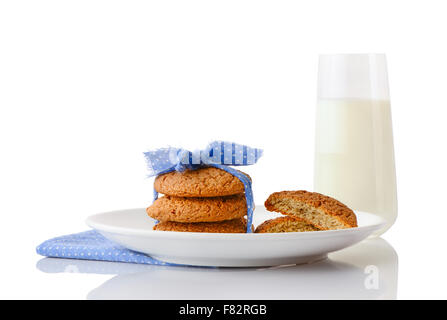 Stack of three homemade oatmeal cookies tied with blue ribbon and halves of cookies on plate and glass of milk Stock Photo