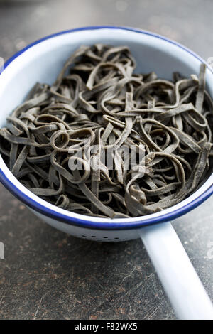cooked black noodles with squid sepia ink in colander