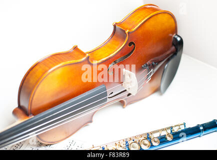 Wood violin body part detail with strings and f-hole, and blue flute part on score Stock Photo