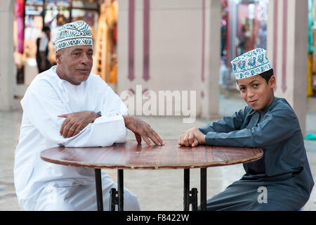 Omani man and his son sitting outside the Mutrah souk in Muscat, the capital of the Sultanate of Oman. Stock Photo
