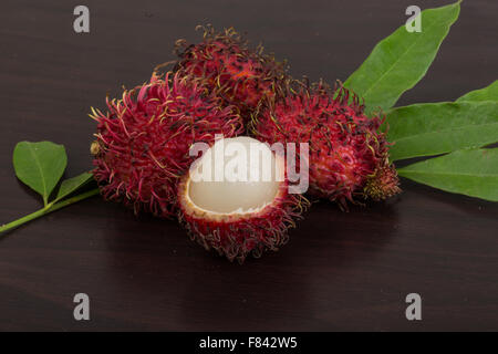 Fresh Rambutan with leaves on the wooden background Stock Photo