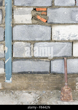 Brick in the block wall of construction site with metal trowel. Stock Photo