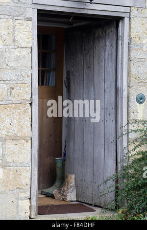 wooden front door with wellington boots in doorway at a countryside cottage Stock Photo