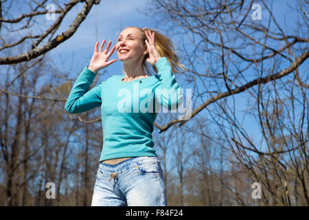 The happy young woman in bright clothes jumps in spring park Stock Photo