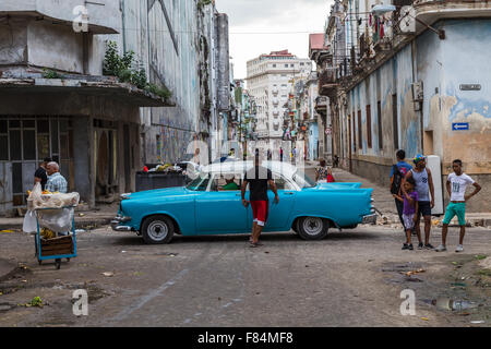Looking over Calle Consulado in Cento Havana, Cuba as a classical car passes some locals on the streets. Stock Photo