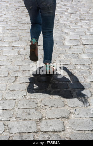 Young woman running on cobbled road Stock Photo
