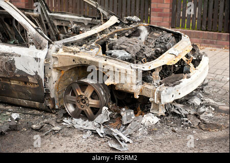 Devastated burnt car in arson fire, white car wreck at the pavement in Poland, spoilt empty car in fire accident, charred car Stock Photo