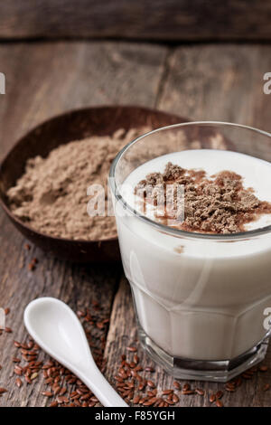 Glass of  yogurt with crushed flax seeds, flax flour in a wooden bowl  on a wooden background Stock Photo