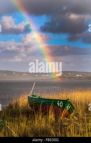 Ardara, County Donegal, Ireland Weather. 6th December 2015. After two days of incessant rain during Storm Desmond a rainbow appears over reed beds and fishing boats on the west coast. Credit:  Richard Wayman/Alamy Live News Stock Photo