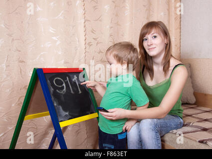 Mother teaches child to emergency phone numbers Stock Photo