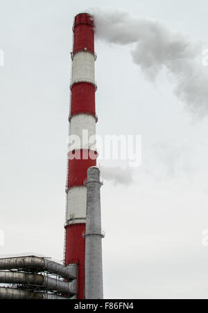Two chimney stacks emit smoke and pollution into the white sky of an unknown industrial city Stock Photo