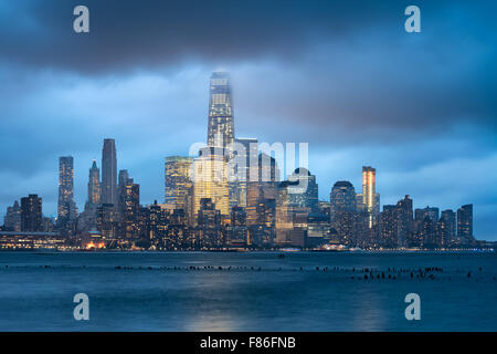 Lower Manhattan and Financial District illuminated skyscrapers with storm clouds, New York City. World Trade Center evening view Stock Photo