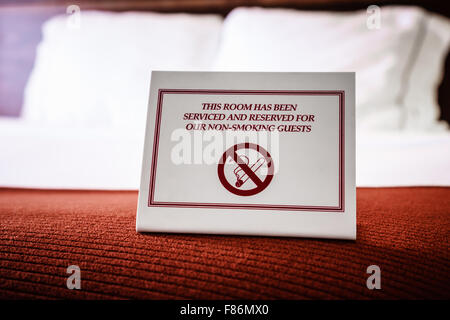 No Smoking Sign on a hotel room bed. Sign reads 'This room has been serviced and reserved for our non-smoking guests' Stock Photo