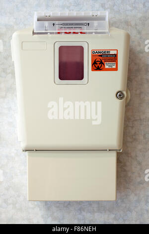 Hospital sharps syringe needle disposal container mounted on a wall Stock Photo