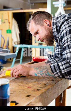 Craftsman sanding a guitar neck in wood at workshop Stock Photo