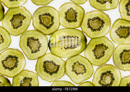 exotic kiwi fruit backlit in studio cut cross and longitudinal sections showing internal seed distribution around central core Stock Photo