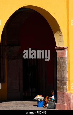 A flower salesperson prepares her merchandise under an arch in San Miguel de Allende, Mexico. Stock Photo